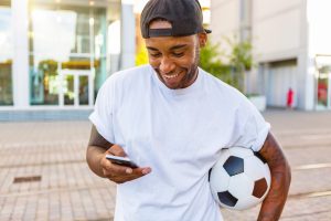 Football bettor checking a phone and setting responsible betting limits