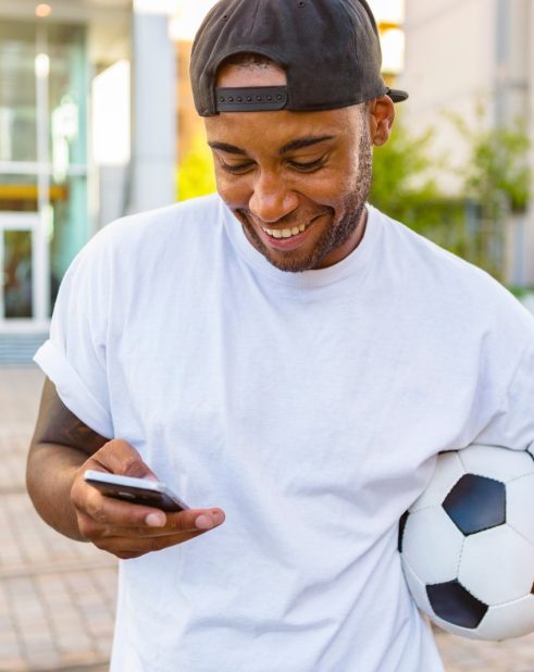 Football bettor checking a phone and setting responsible betting limits
